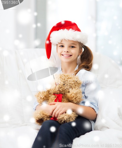 Image of smiling girl in santa helper hat with teddy bear
