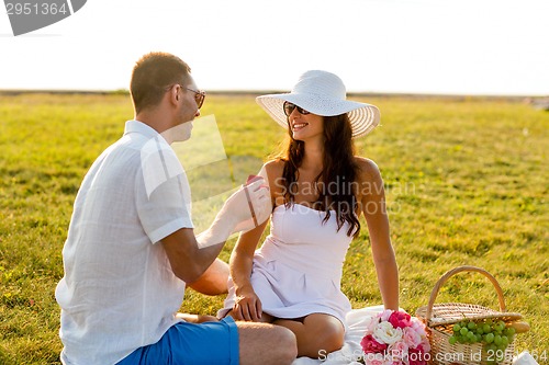 Image of smiling couple with small red gift box on picnic