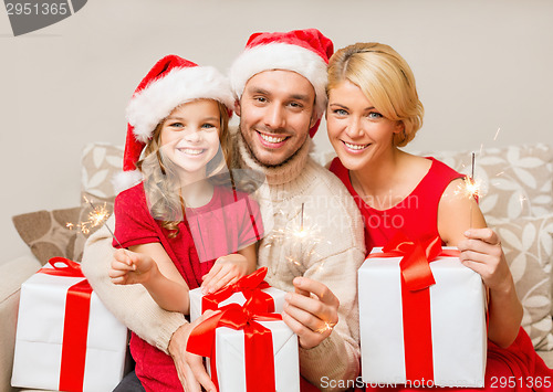 Image of smiling family holding gift boxes and sparkles