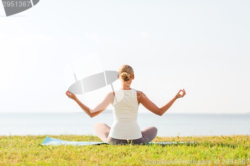 Image of woman making yoga exercises outdoors