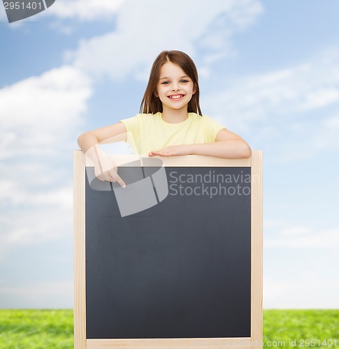 Image of happy little girl pointing finger to blackboard