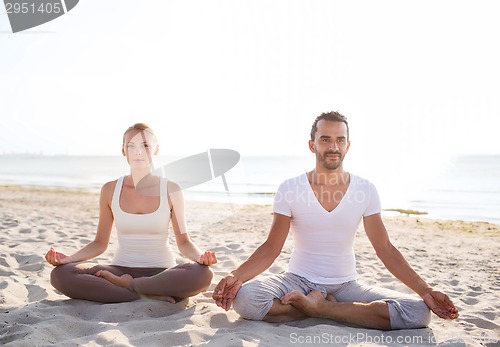 Image of smiling couple making yoga exercises outdoors