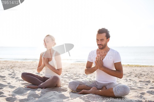 Image of smiling couple making yoga exercises outdoors