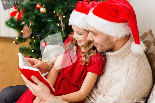 Image of smiling father and daughter reading book