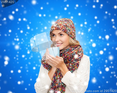 Image of smiling young woman in winter clothes with cup