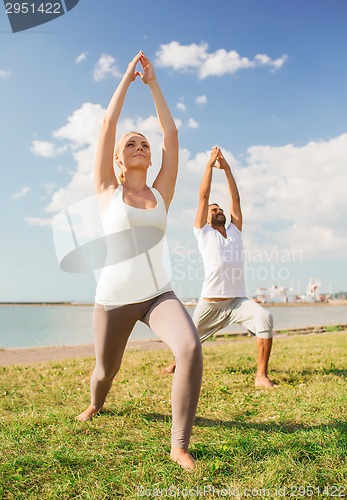 Image of couple making yoga exercises outdoors