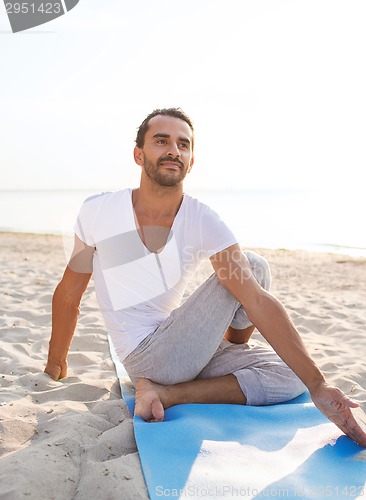 Image of man doing yoga exercises outdoors