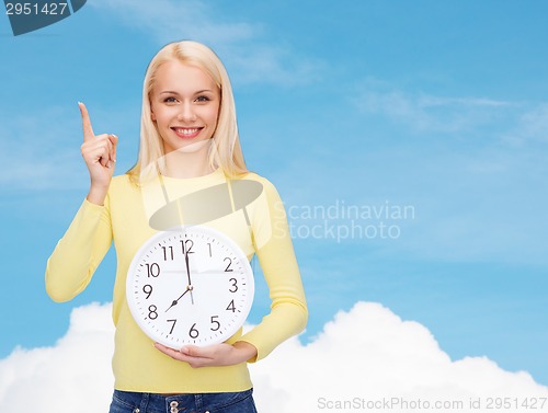 Image of student with wall clock and finger up