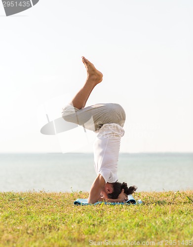 Image of man making yoga exercises outdoors