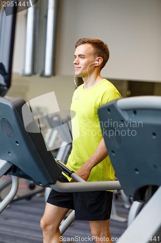 Image of man with smartphone exercising on treadmill in gym