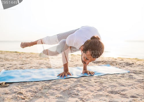 Image of man doing yoga exercises outdoors