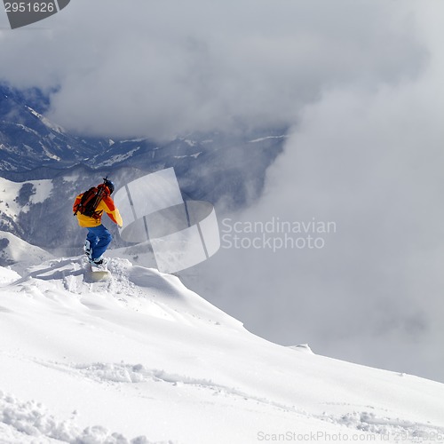 Image of Snowboarder on off-piste slope an mountains in mist
