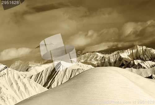 Image of Sepia off-piste snowy slope and cloudy mountains