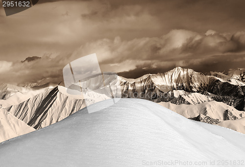 Image of Top of off-piste snowy slope and sepia mountains