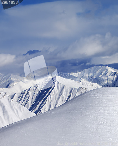 Image of Top of off-piste snowy slope and cloud mountains