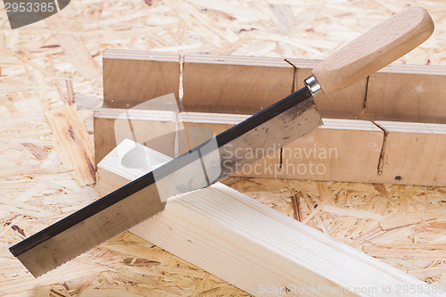 Image of Hand saw cutting through a beam of wood