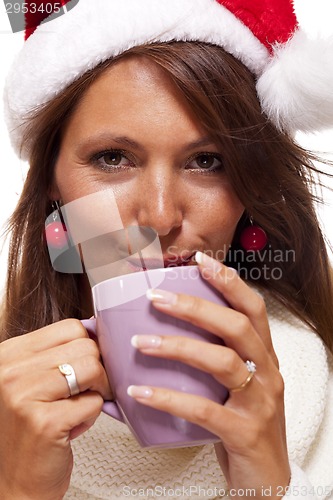 Image of Cold young woman in a Santa hat sipping coffee tea