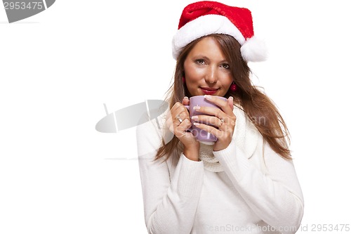 Image of Cold young woman in a Santa hat sipping coffee tea