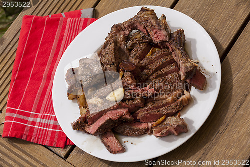 Image of Plate of Grilled Steak and Garlic with Red Napkin