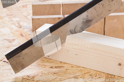 Image of Hand saw cutting through a beam of wood