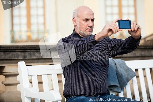 Image of Man taking a photograph with his mobile