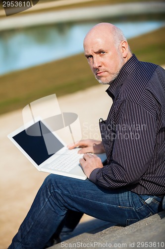 Image of Man sitting on a bench using a laptop