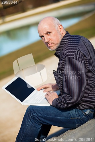 Image of Man sitting on a bench using a laptop