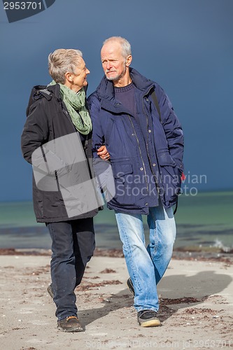 Image of happy elderly senior couple walking on beach