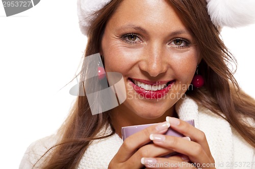 Image of Cold young woman in a Santa hat sipping coffee tea