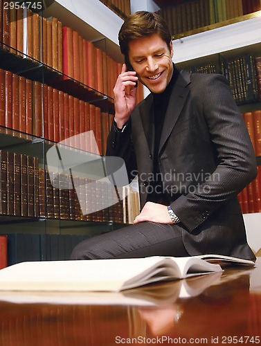 Image of in office looking at book and talking on phone