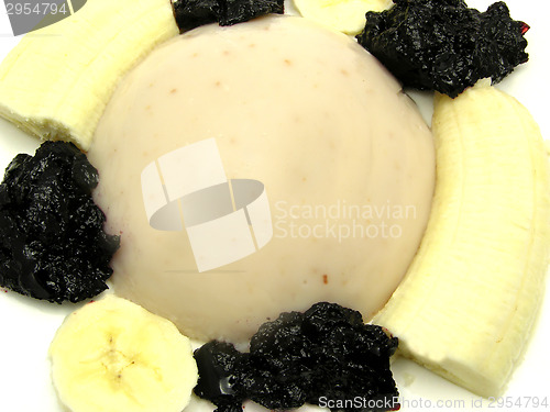 Image of Almond pudding with banana and blueberry jam on a white plate