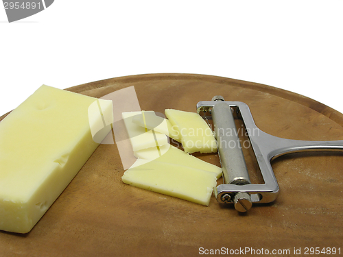Image of Hard cheese on wooden plate with cheese slicer