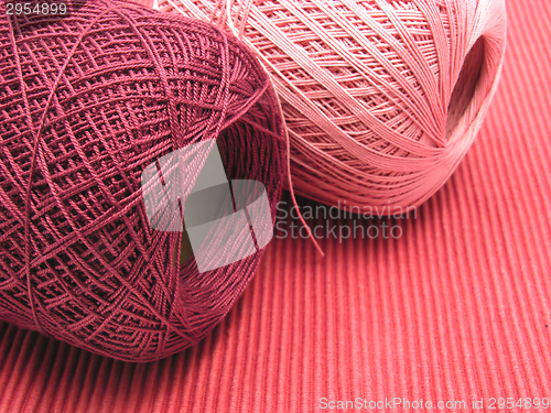 Image of Two balls of wool  on a red background