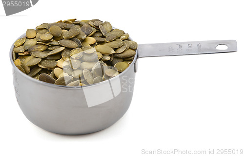 Image of Green pumpkin seeds in a cup measure