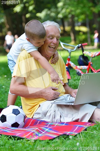 Image of grandfather and child using laptop