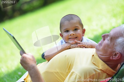 Image of grandfather and child in park using tablet