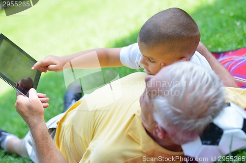 Image of grandfather and child in park using tablet