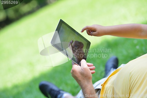 Image of grandfather and child in park using tablet