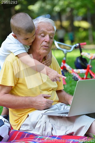Image of grandfather and child using laptop
