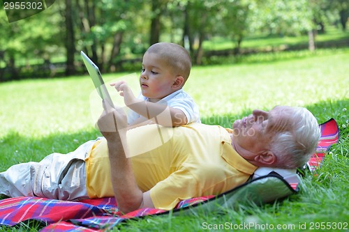 Image of grandfather and child in park using tablet