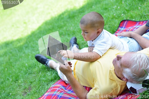 Image of grandfather and child in park using tablet