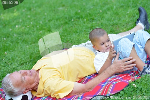 Image of grandfather and child in park using tablet