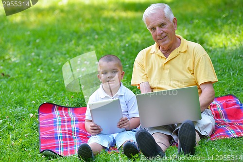 Image of grandfather and child using laptop