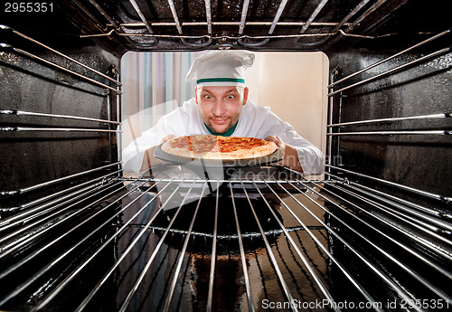 Image of Chef cooking pizza in the oven.