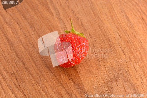 Image of close up of small strawberry on wood