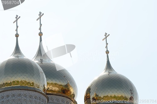 Image of Golden cupola and christian cross on church against blue sky