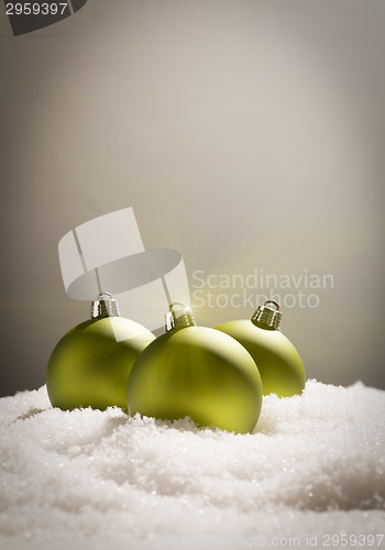 Image of Green Christmas Ornaments on Snow Over a Grey Background