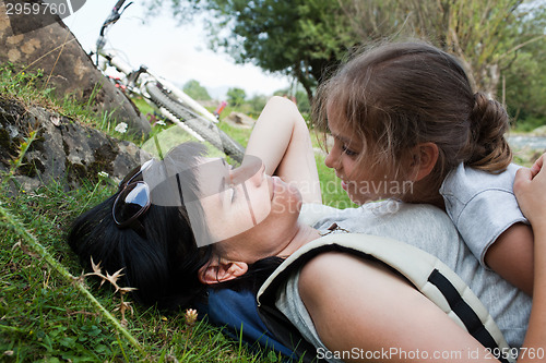 Image of Mother and daughter relaxing on a grass