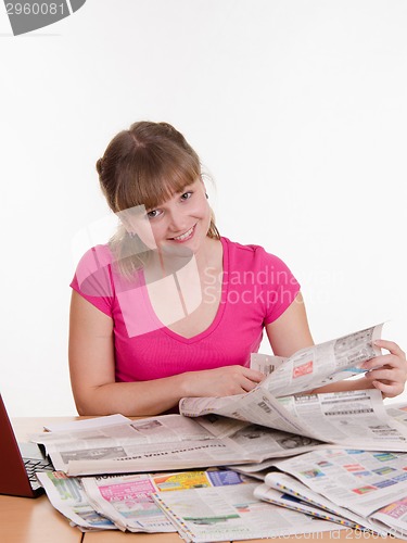 Image of Girl looking for the right ad in newspaper