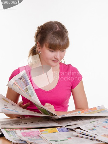 Image of girl thumbs through the newspaper to find right ads